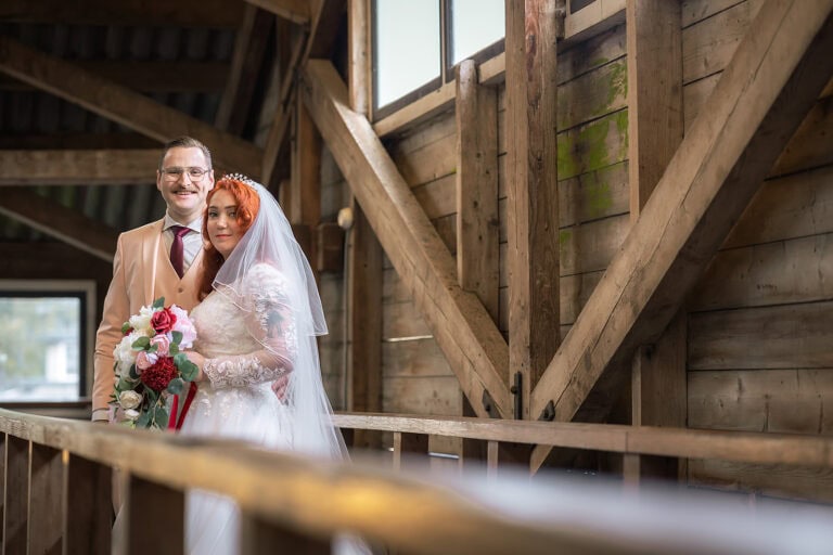 Bruidspaar Natalie en Ralf bij de bootveiling aan de Broek op Langedijk met houten schuur en sfeervolle trouwcompositie
