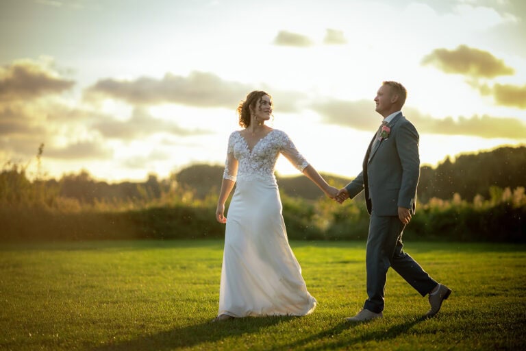 Nienke en Steven lopend over een grasveld tijdens zonsondergang in Geestmerambacht